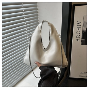 Detail view of white asymmetric triangular handbag with glossy finish and silver ball chain