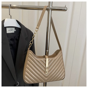 Détail du sac beige matelassé avec surpiqûres à chevrons et fermoir doré en métal