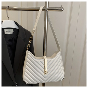 Détail du matelassage en V blanc avec chaîne dorée et boucle métallique sur le sac chic