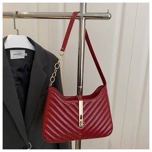 Détail du sac en cuir rouge matelassé avec fermoir doré et texture à motif de chevrons