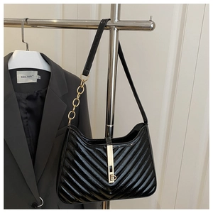 Détail du sac noir verni avec surpiqûres en V et chaîne dorée élégante de luxe