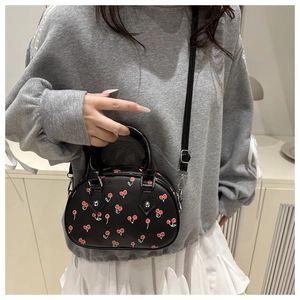Crossbody bag with cherry print and adjustable strap shown on a model in daily life