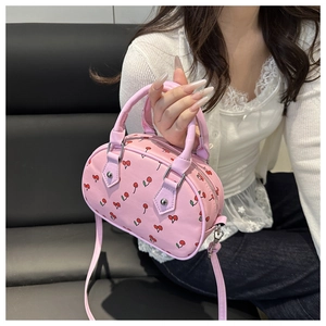 Detail of pink cherry print handbag featuring leather handles and silver hardware hooks