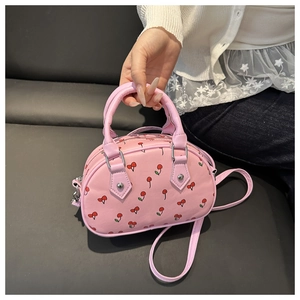 Detail of pink PU leather handbag with cherry print and silver metal hardware accents