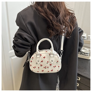 Close-up of red cherry print bag with silver rivet details and metallic zipper