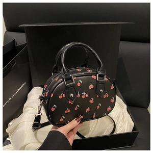 Detail of black cherry print handbag featuring silver stud accents and branded gift box