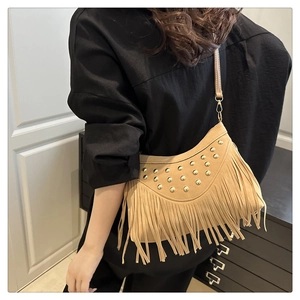 Detail of camel suede saddle bag featuring gold studs and long fringe tassels