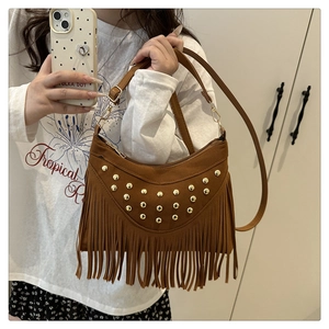 Detail view of brown suede saddle bag with gold studs and tassel fringe decor