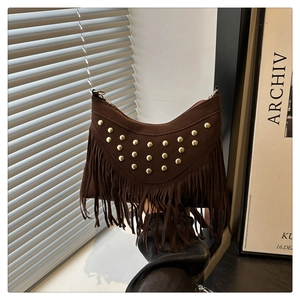 Detail of brown suede crossbody bag with gold studs and long fringe in western style