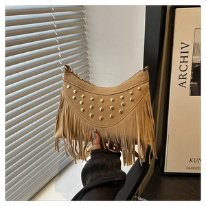 Close-up of khaki suede saddle bag featuring gold rivets and long fringe details