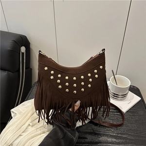 Brown suede bohemian saddle bag with golden studs and long fringe detail shown in hand