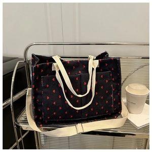 Detail of dark blue corduroy tote bag with red hearts and adjustable shoulder strap