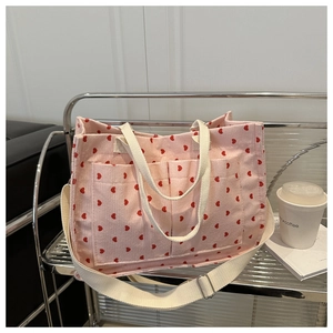 Detail of pink corduroy tote bag with red hearts, dual front pockets and adjustable strap