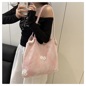 Detail of pink floral embroidery and thick woven rope handle on summer bucket tote bag