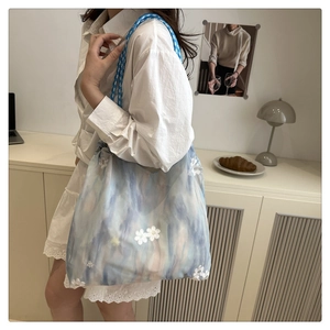 Detail of blue gradient tote bag with white flower embroidery and woven rope handle