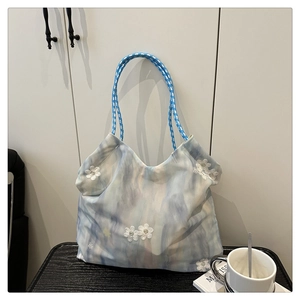 Detailed close-up of tote bag featuring 3D white flower appliqués and woven rope handles