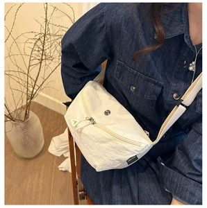 Détail du sac bandoulière en nylon blanc cassé avec une sangle contrastée noir et blanc