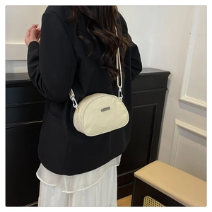 Detail of a beige half-moon nylon crossbody bag with adjustable strap on a model