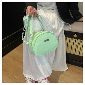 Detail of mint green nylon crossbody bag with adjustable strap held by a model