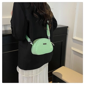 Detail of mint green nylon crescent crossbody bag with branded metal logo and wide strap
