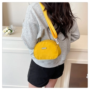 Detail of a bright yellow nylon crescent crossbody bag with a wide strap and metal logo
