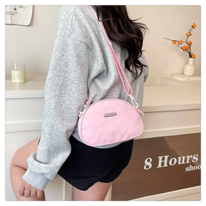 Detail of pink nylon crescent bag featuring adjustable strap and metallic logo plate