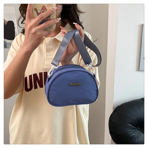 Detail of dark blue nylon crossbody bag with adjustable wide strap and round brand tag