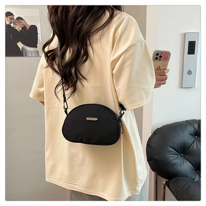 Modern black nylon crescent crossbody bag with adjustable strap worn by model