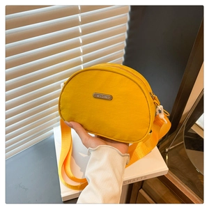 Detail of yellow nylon crescent bag featuring JING PIN metal tag and wide strap