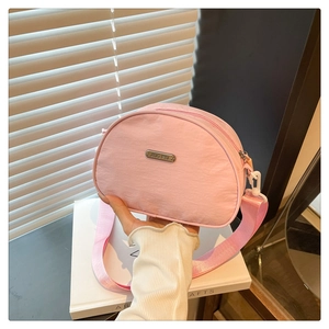Detail of pink crescent nylon bag showing the metal JING PIN logo and wide strap