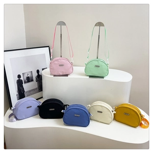 Detailed macro view of seven vibrant nylon crossbody bags featuring a crescent shape and metal logo