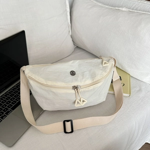 Sac demi-lune chic en nylon beige avec bandoulière réglable sur fond décontracté