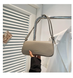 Close-up of minimalist taupe shoulder bag featuring pebble leather texture and knot detail