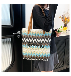 Detail of woven straw tote bag with Summer embroidery and leather shoulder straps