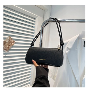 Detail of black pebbled leather underarm bag with gold logo and slim shoulder strap
