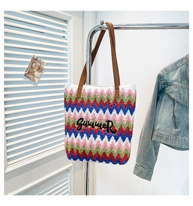 Detail view of woven summer tote bag with colorful wave patterns and Summer embroidery