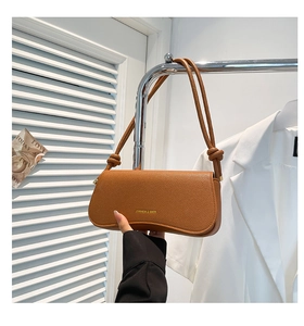 Detail of brown litchi pattern leather shoulder bag with knotted strap and gold logo