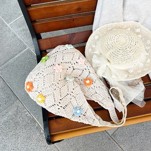 Sac fourre-tout en tricot beige avec marguerites au crochet sur un banc en bois