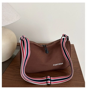 Détail du sac en toile marron café avec bandoulière rayée et logo blanc imprimé