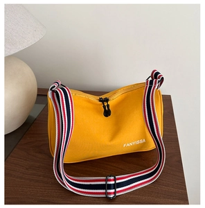 Détail d'un sac à bandoulière jaune avec sangle tissée rayée et double fermeture éclair
