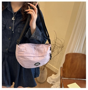 Detail of light purple nylon crescent bag with adjustable strap in a home setting