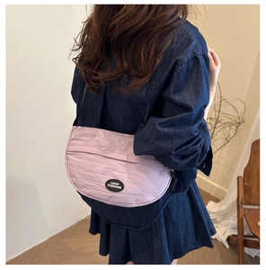 Side view of light purple crescent waist bag on model wearing dark blue denim dress