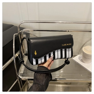 Detail of piano-themed crossbody bag with black and white keys and I LIKE MUSIC text