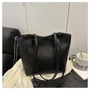 Minimalist black tote bag displayed in a cozy lifestyle setting with a coffee cup and books