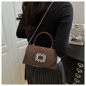 Crossbody view of a brown suede handbag with a luxury rhinestone buckle and gold chain