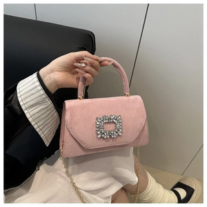 Detail of pink suede handbag featuring a large square crystal buckle and gold chain strap
