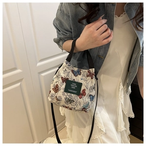 Detail of vintage butterfly jacquard bucket bag with brand label and crossbody strap