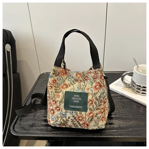 Detail of floral tapestry bucket bag with adjustable strap on a dark wooden table