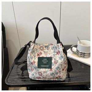 Floral canvas tote bag with adjustable shoulder strap and green label on textured table