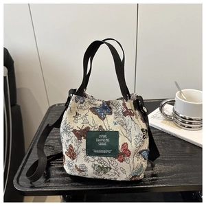 Detail of retro drawstring bucket tote bag with colorful butterfly embroidery and logo patch